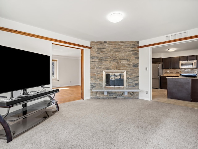 living room with a stone fireplace, baseboards, and light carpet