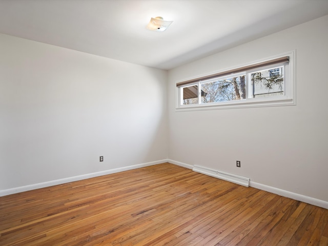 spare room with a baseboard heating unit, light wood-style flooring, and baseboards