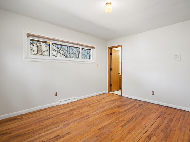 unfurnished room with visible vents, light wood-type flooring, and baseboards