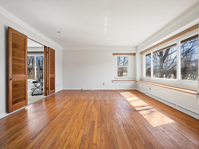 unfurnished room featuring visible vents, light wood-style floors, baseboards, and a baseboard radiator