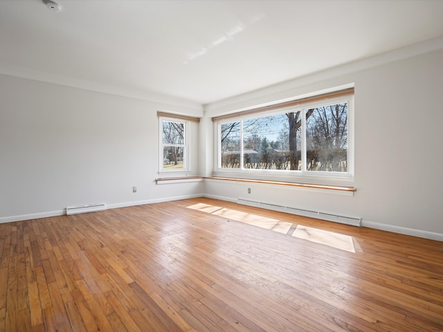 empty room featuring baseboard heating, baseboards, and wood-type flooring