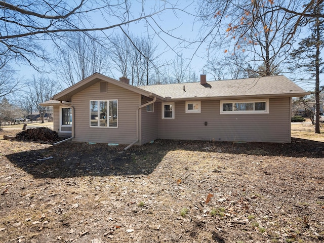 back of property with a chimney and a shingled roof