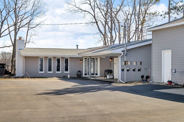 view of front facade with an attached garage, brick siding, driveway, and a chimney