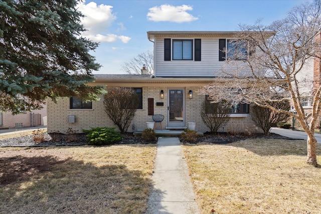 traditional-style house featuring a front lawn and brick siding