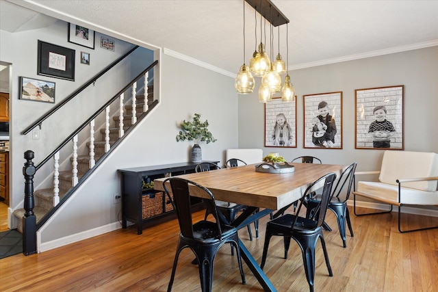 dining space with light wood-style flooring, stairs, baseboards, and ornamental molding