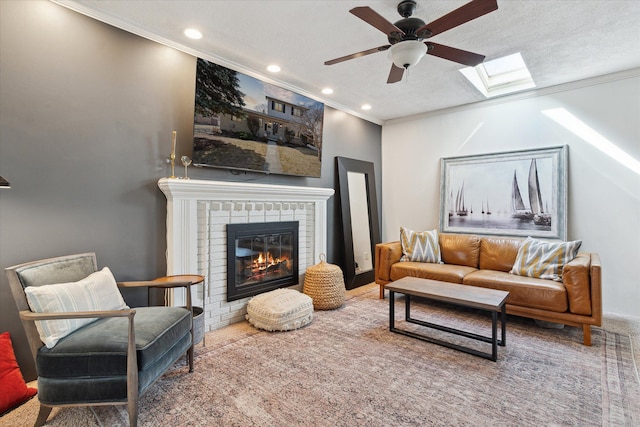 living room with a fireplace, a skylight, a textured ceiling, and ornamental molding