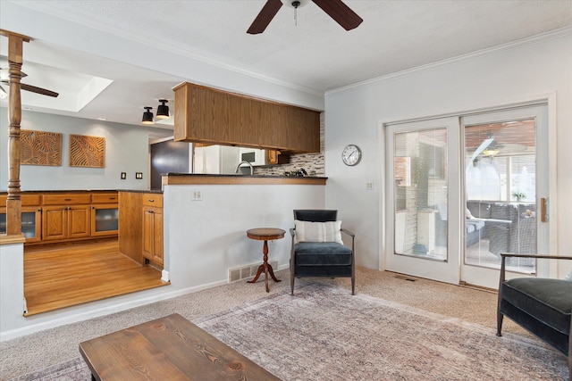 living area with light colored carpet, crown molding, a ceiling fan, and visible vents