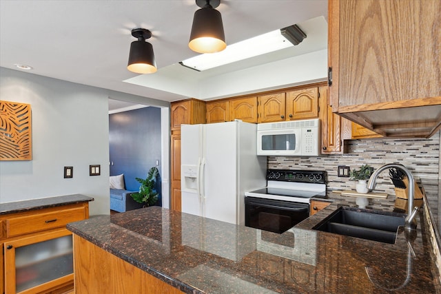 kitchen with decorative backsplash, dark stone countertops, brown cabinetry, white appliances, and a sink