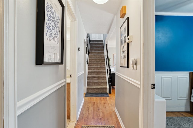 corridor featuring wainscoting, stairs, and light wood-style floors