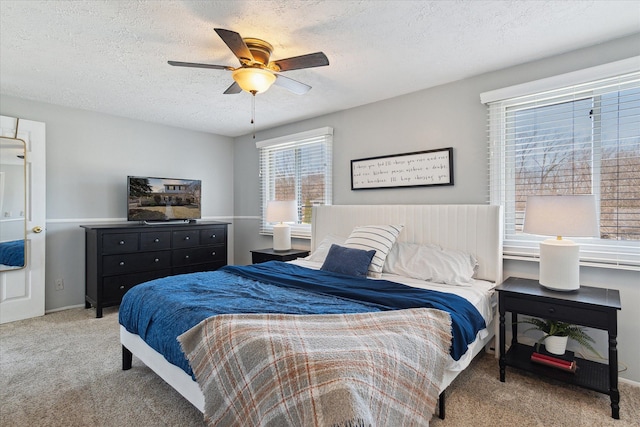 carpeted bedroom with ceiling fan and a textured ceiling