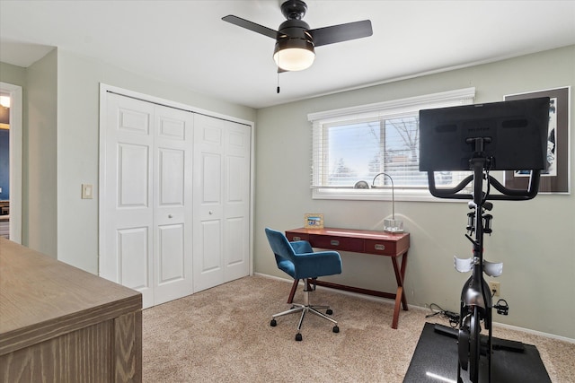 carpeted office space featuring a ceiling fan and baseboards