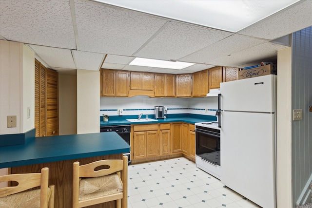 kitchen with dark countertops, under cabinet range hood, light floors, white appliances, and a sink