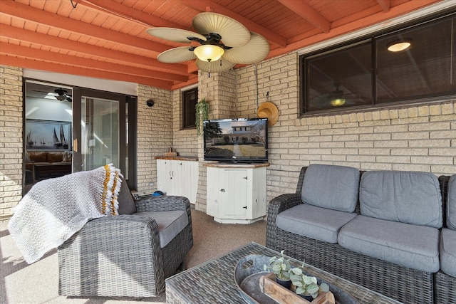 living area featuring beam ceiling, carpet flooring, brick wall, and ceiling fan