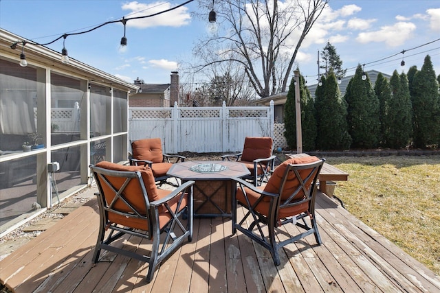 wooden terrace with fence, a sunroom, and an outdoor fire pit