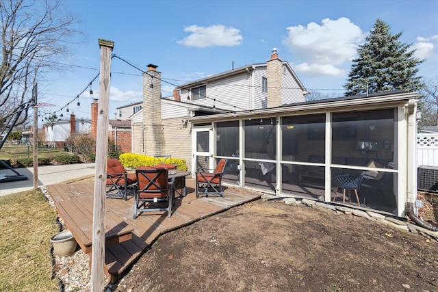 rear view of house with a wooden deck, a sunroom, and a chimney