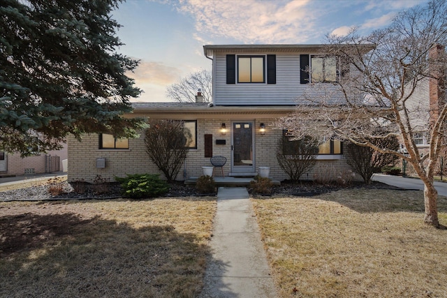 traditional-style house featuring brick siding and a front lawn