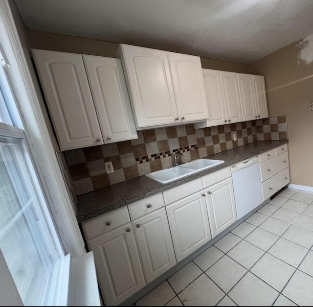 kitchen with light tile patterned floors, a sink, white cabinets, dishwasher, and tasteful backsplash