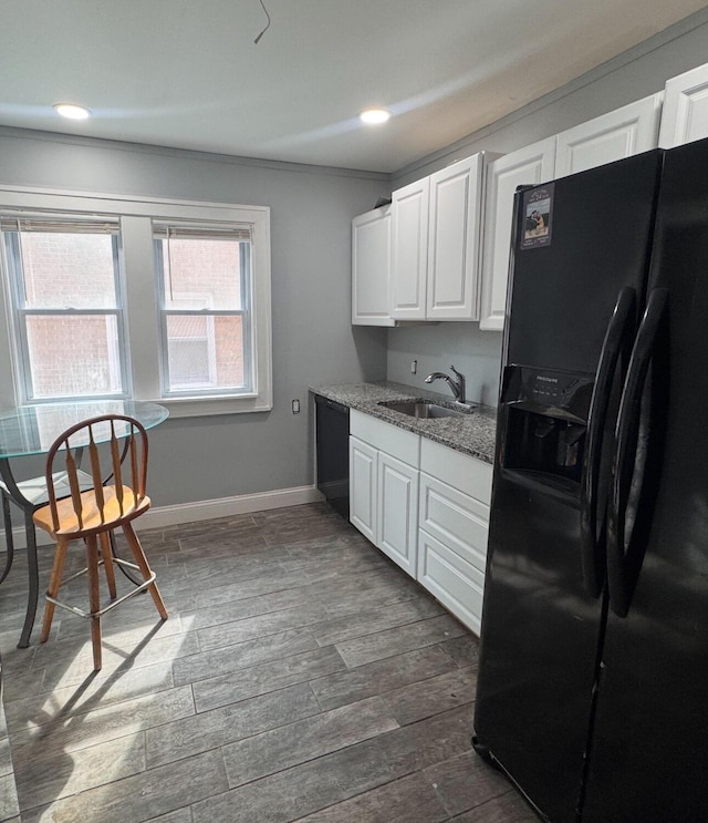 kitchen featuring black appliances, a sink, dark wood finished floors, baseboards, and light stone countertops