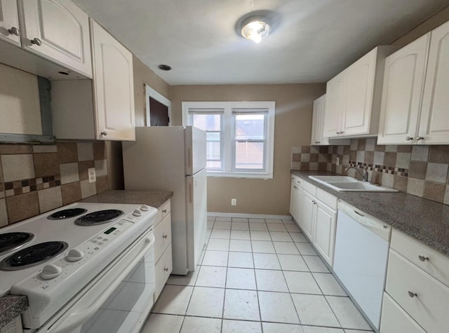 kitchen with a sink, white appliances, white cabinets, light tile patterned floors, and baseboards