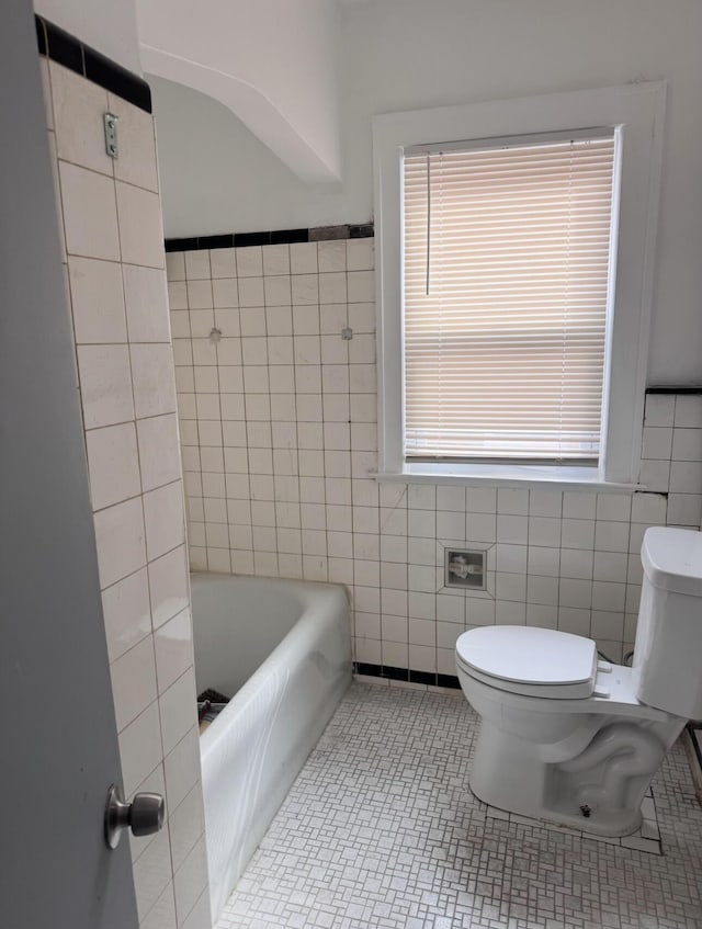 full bath with tile patterned floors, toilet, tile walls, and plenty of natural light