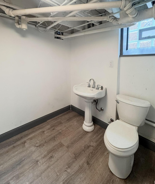 bathroom with toilet, baseboards, and wood finished floors