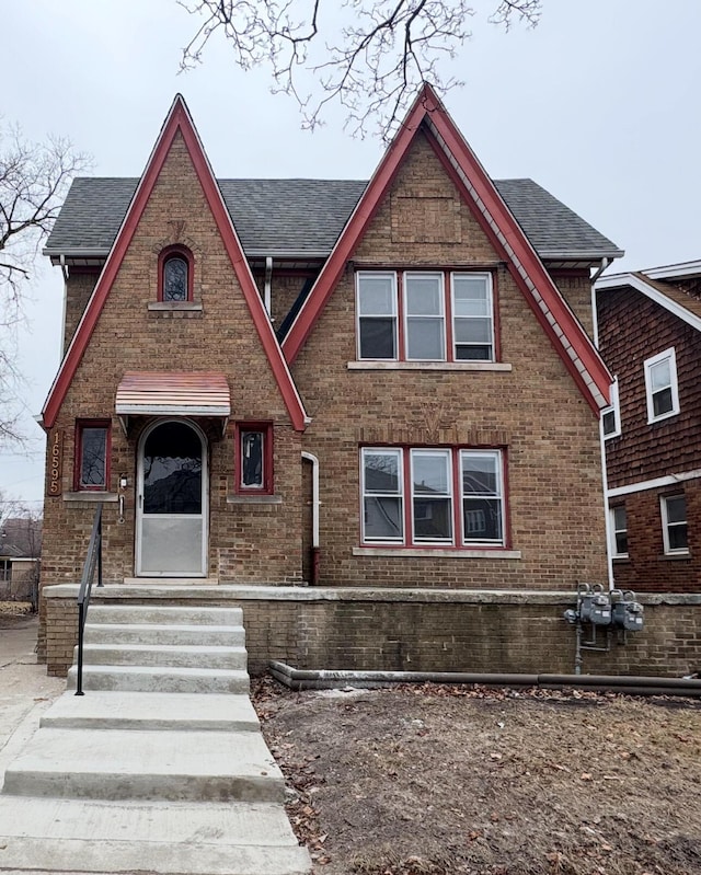 view of front of house with entry steps, brick siding, and a shingled roof