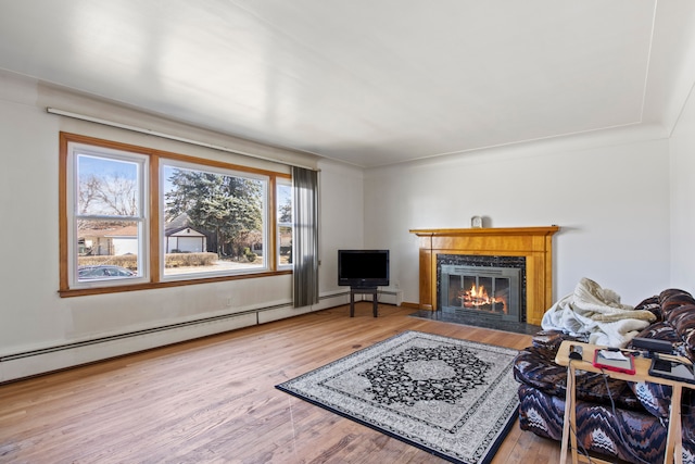 living room with a glass covered fireplace, a baseboard heating unit, and wood finished floors