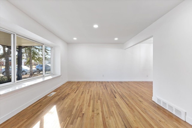 empty room with visible vents, light wood-type flooring, and baseboards