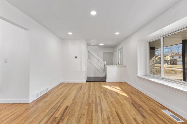 spare room with visible vents, stairway, light wood-type flooring, and baseboards