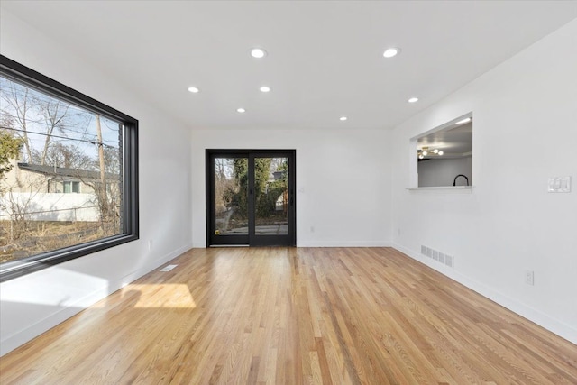 empty room featuring visible vents, light wood-style flooring, and baseboards