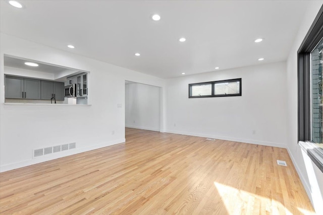 unfurnished living room featuring light wood-type flooring, visible vents, baseboards, and recessed lighting