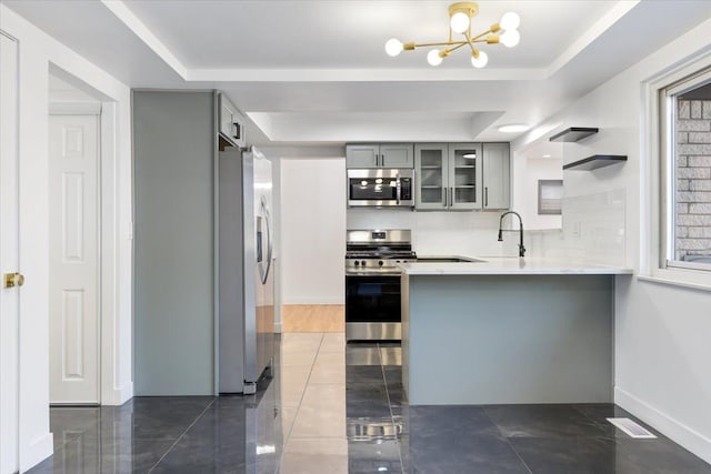 kitchen featuring a barn door, a raised ceiling, appliances with stainless steel finishes, and gray cabinetry