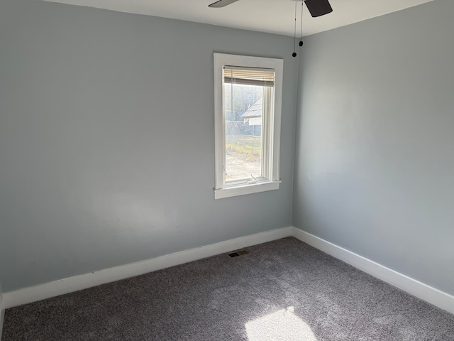 empty room featuring visible vents, baseboards, a ceiling fan, and dark carpet