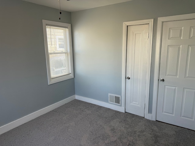 unfurnished bedroom with carpet, visible vents, and baseboards