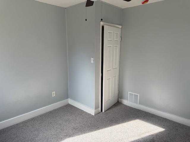 carpeted spare room with a ceiling fan, visible vents, and baseboards