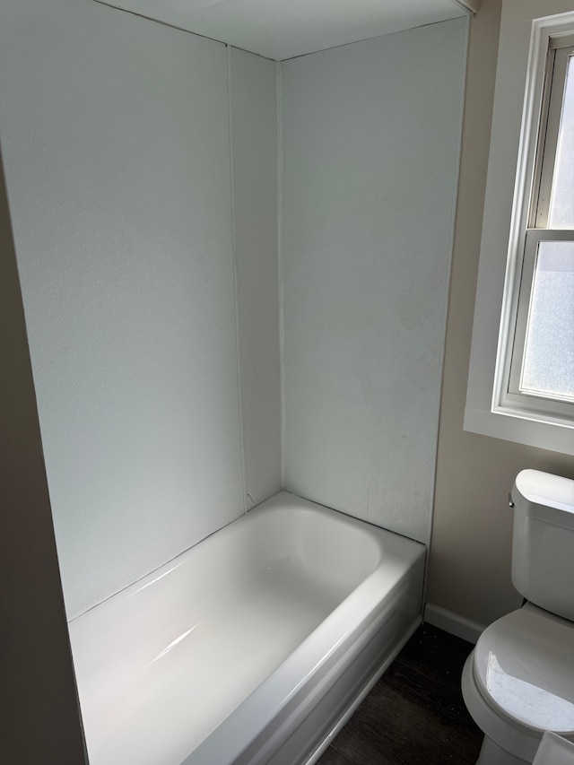 full bathroom featuring wood finished floors, toilet, and a bath