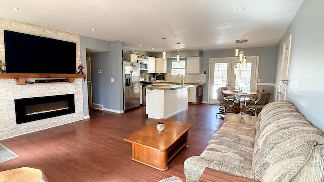 living area with dark wood finished floors, visible vents, a fireplace, and baseboards