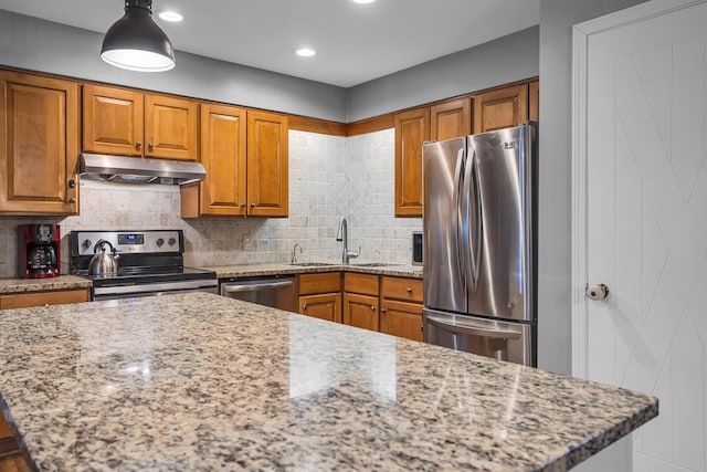 1307 Winston Dr, Jackson, MI 49203 - kitchen featuring under cabinet range hood, appliances with stainless steel finishes, brown cabinetry, and a sink