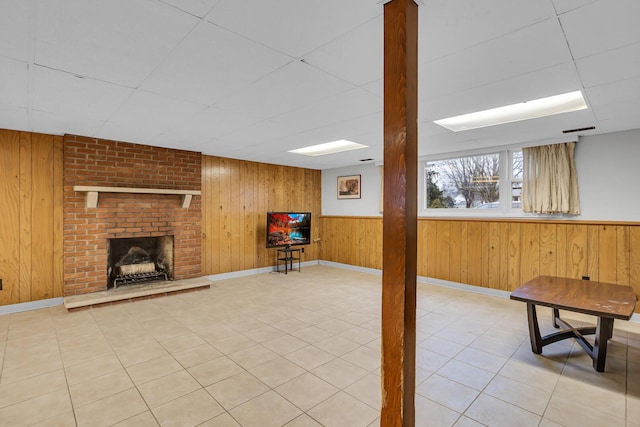 1307 Winston Dr, Jackson, MI 49203 - basement with wooden walls, visible vents, a brick fireplace, a drop ceiling, and tile patterned floors