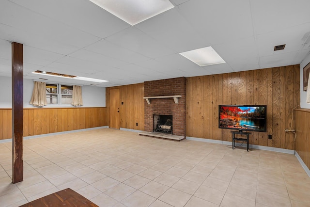 1307 Winston Dr, Jackson, MI 49203 - unfurnished living room featuring wood walls, a brick fireplace, and a paneled ceiling