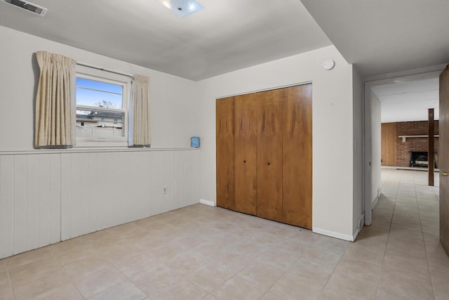 1307 Winston Dr, Jackson, MI 49203 - unfurnished bedroom with a closet, visible vents, a brick fireplace, and a wainscoted wall
