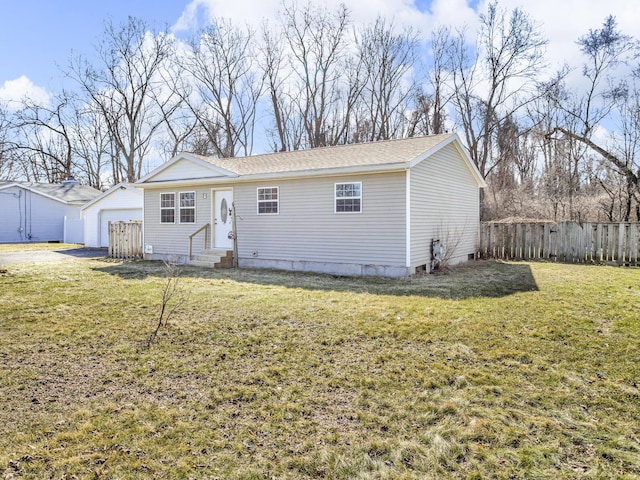 single story home featuring entry steps, a front lawn, fence, and an outdoor structure