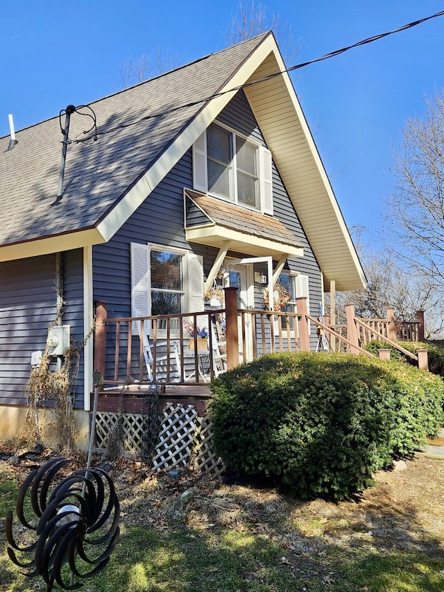 back of property with a deck and roof with shingles