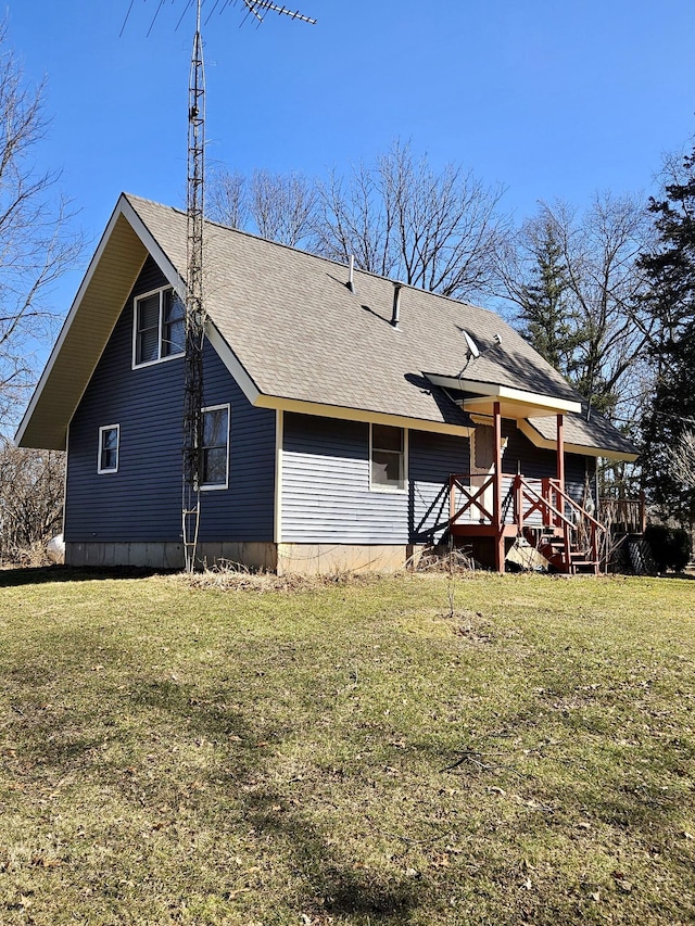 back of property with a wooden deck, a shingled roof, and a yard