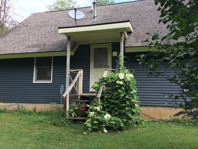 property entrance featuring a yard and a shingled roof