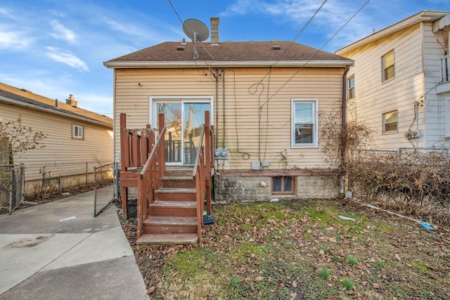 rear view of property with a shingled roof, a patio, and fence