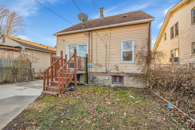 rear view of house with roof with shingles and fence