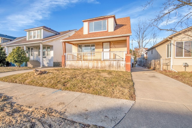 view of front of home featuring a porch, concrete driveway, a front lawn, and a shingled roof