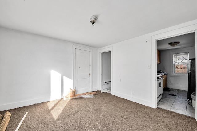 carpeted spare room featuring a baseboard heating unit and baseboards