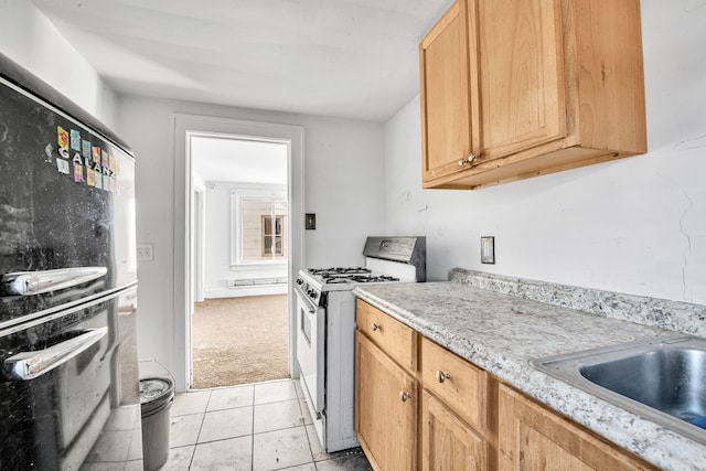 kitchen featuring light colored carpet, light countertops, white gas range oven, light tile patterned floors, and a sink